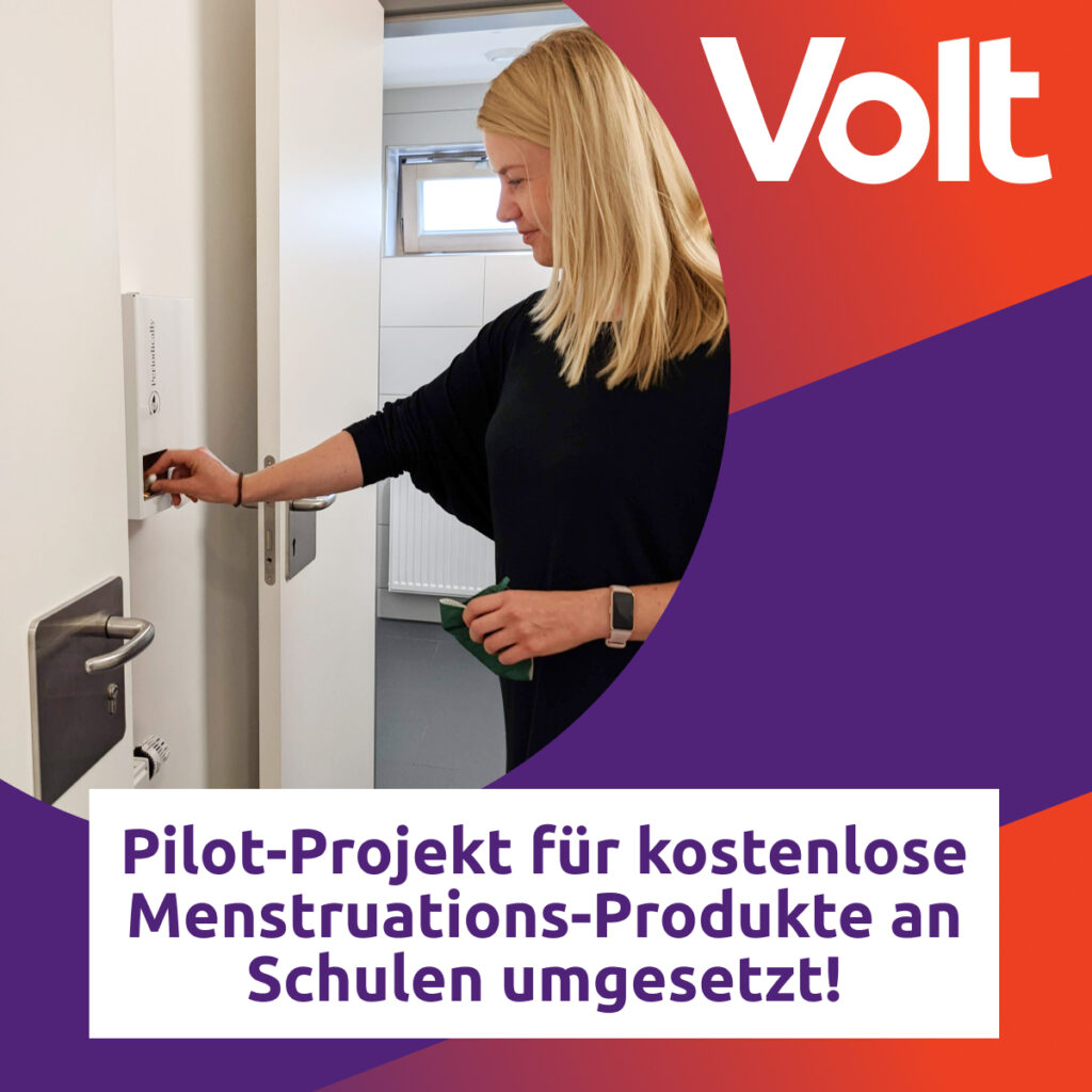 Britta Wollkopf, Stadtverordnete für Volt in Frankfurt, betrachtet einen Spender für Kostenlose Menstruationsprodukte an Schulen. Die Bildunterschrift lautet "Pilot-Projekt für kostenlose Menstruations-Produkte an Schulen umgesetzt!"